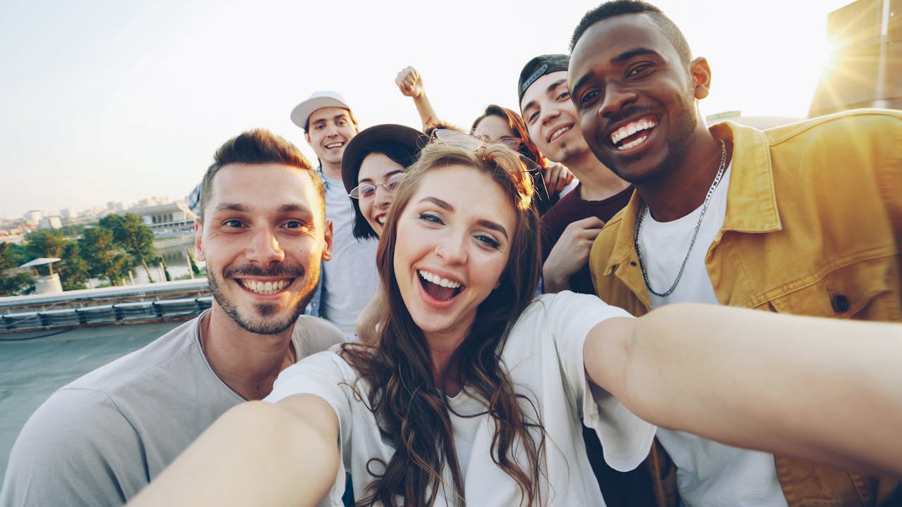 Group of young friends enjoying a sunny day outdoors, smiling and posing for a selfie.