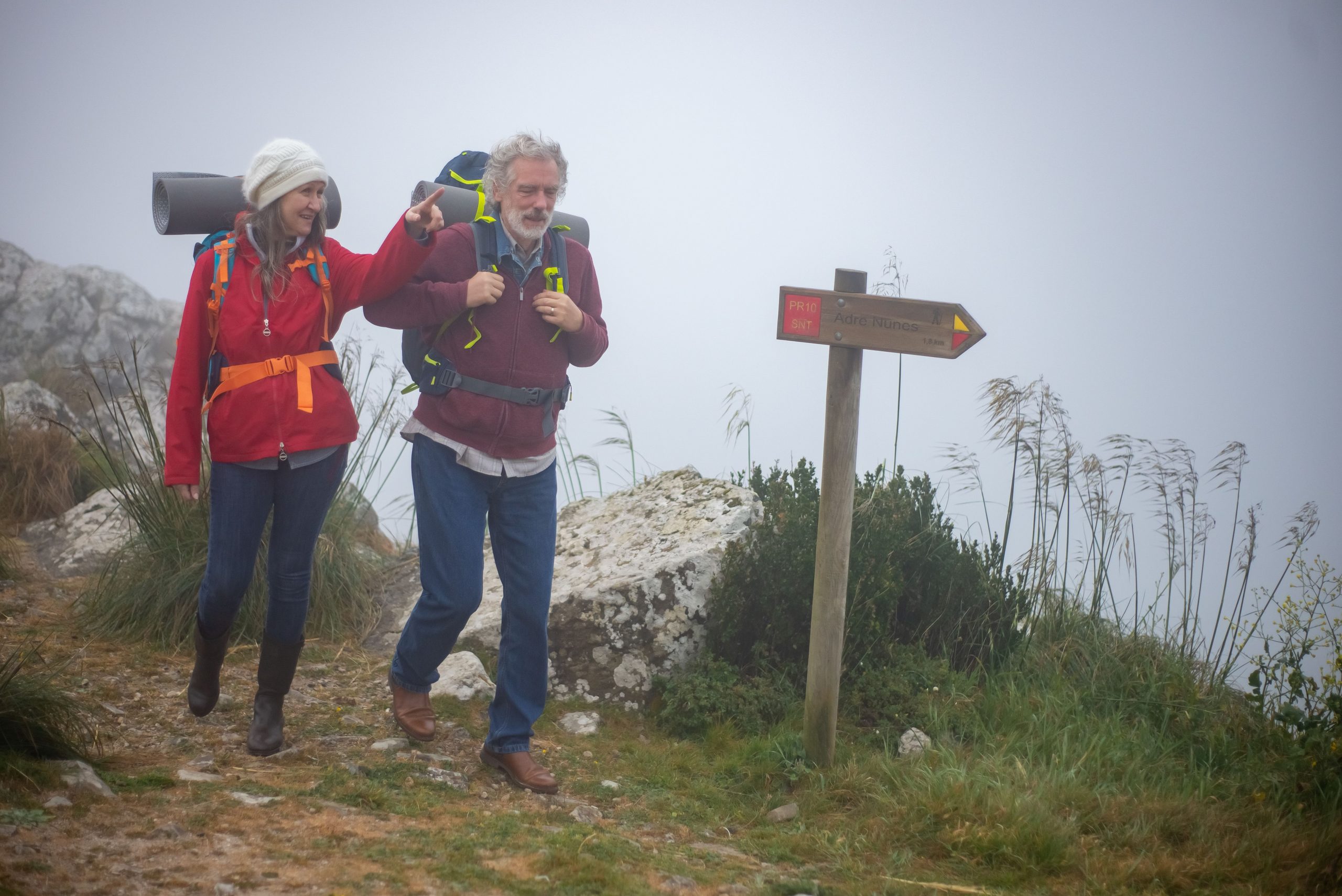 Senior couple enjoys a misty hike through scenic Portugal, embracing adventure.